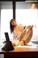 A woman sitting on top of a bed next to a laptop computer.