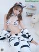 A woman in a cow costume sitting on a bed.