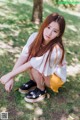 A young woman sitting on the ground in a park.