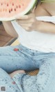 A woman sitting on the ground eating a slice of watermelon.