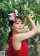 A woman in a red dress holding a pink flower in her hair.