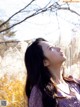 A woman standing in a field looking up at the sky.