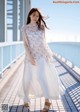 A woman in a white dress standing on a bridge.