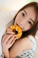 A woman is holding a donut in her mouth.