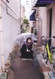 A woman sitting on the ground holding an umbrella.