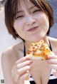 A woman in a bikini eating a slice of pizza.