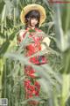 A woman in a red dress and straw hat standing in a field.