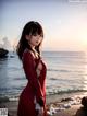 A woman in a red dress standing on a beach.