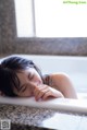 A woman laying in a bathtub with her eyes closed.