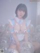 A woman in a blue and white dress sitting in a bunch of balloons.