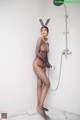 A woman in a bunny costume is taking a shower.