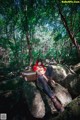 A woman sitting on a rock in the woods.