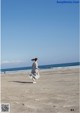 A woman in a striped dress running on the beach.