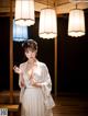 A woman in a white kimono standing in a room.