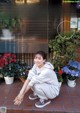 A woman sitting on the ground in front of a flower shop.