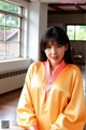 A woman in a yellow robe sitting on the floor.